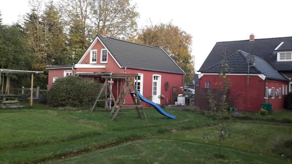 a playground in a yard next to a red house at Sommerhaus (am Landhaus von Felde) in Esens