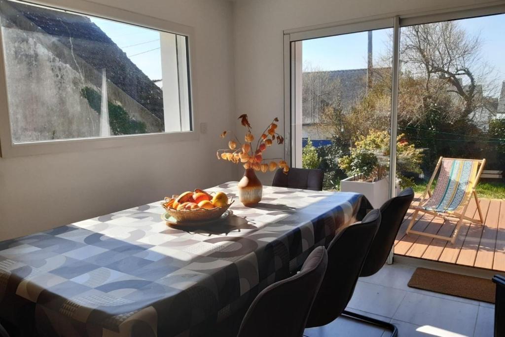 a table with a bowl of fruit in a room with windows at Maison Tamaris avec jardin et clos in Quiberon