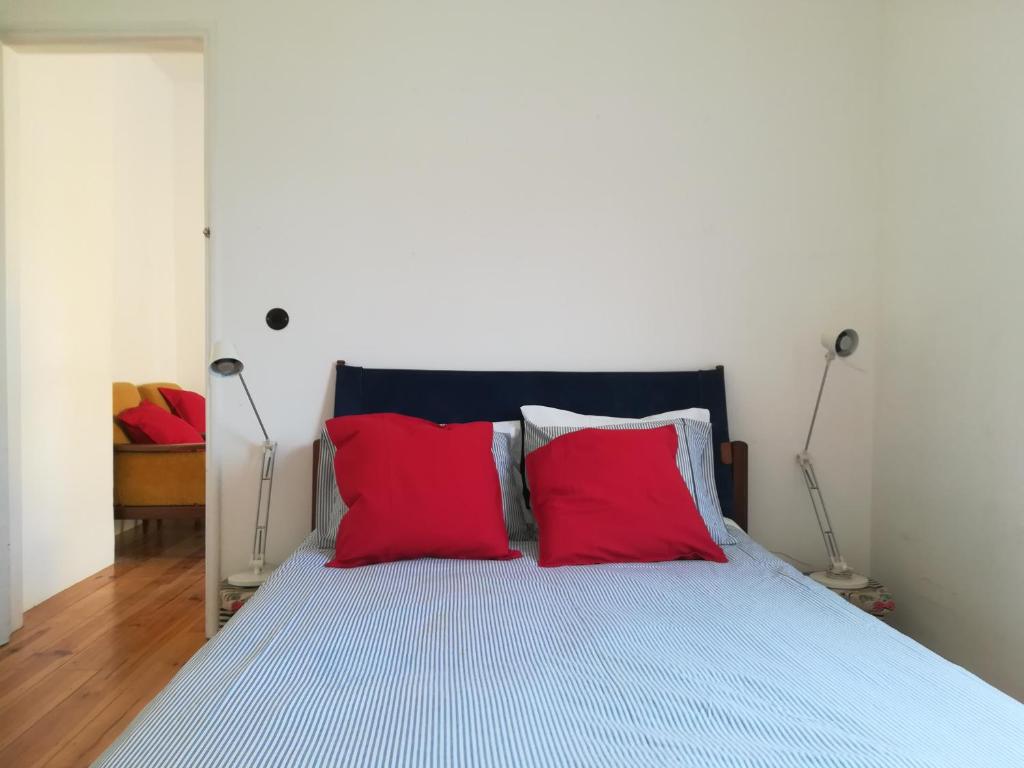 a bedroom with a bed with two red pillows at Casa do Cristo Rei in Almada