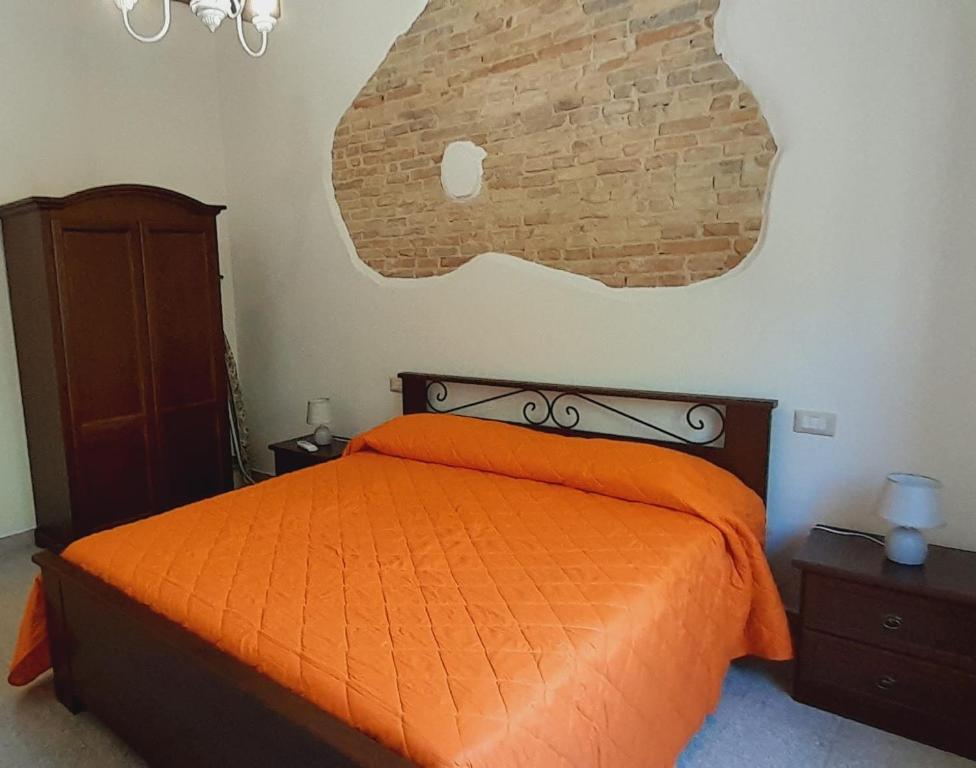a bedroom with an orange bed and a brick wall at Sindaro house in Messina