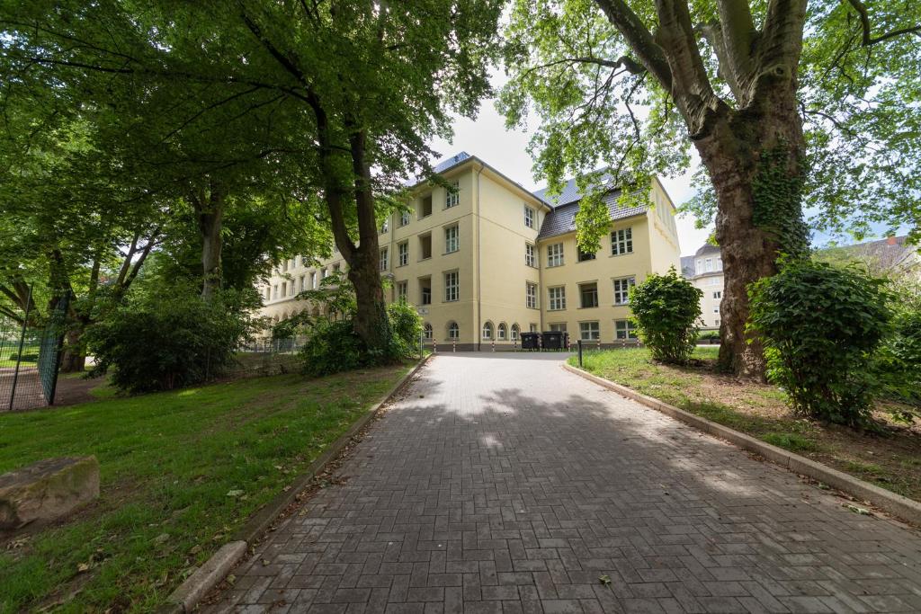 a cobblestone street in front of a large white building at Lunas Appartements in der alten Schule Essen in Essen