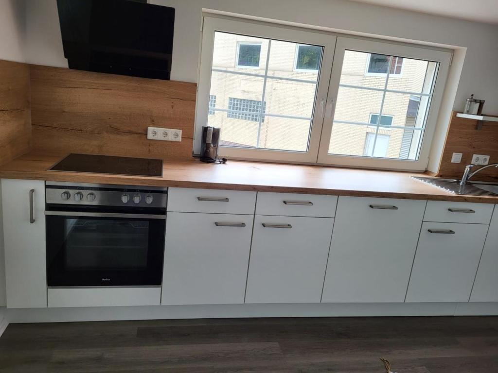 a kitchen with white cabinets and a stove and a window at KaTi Wohnung 2 in Knüllwald