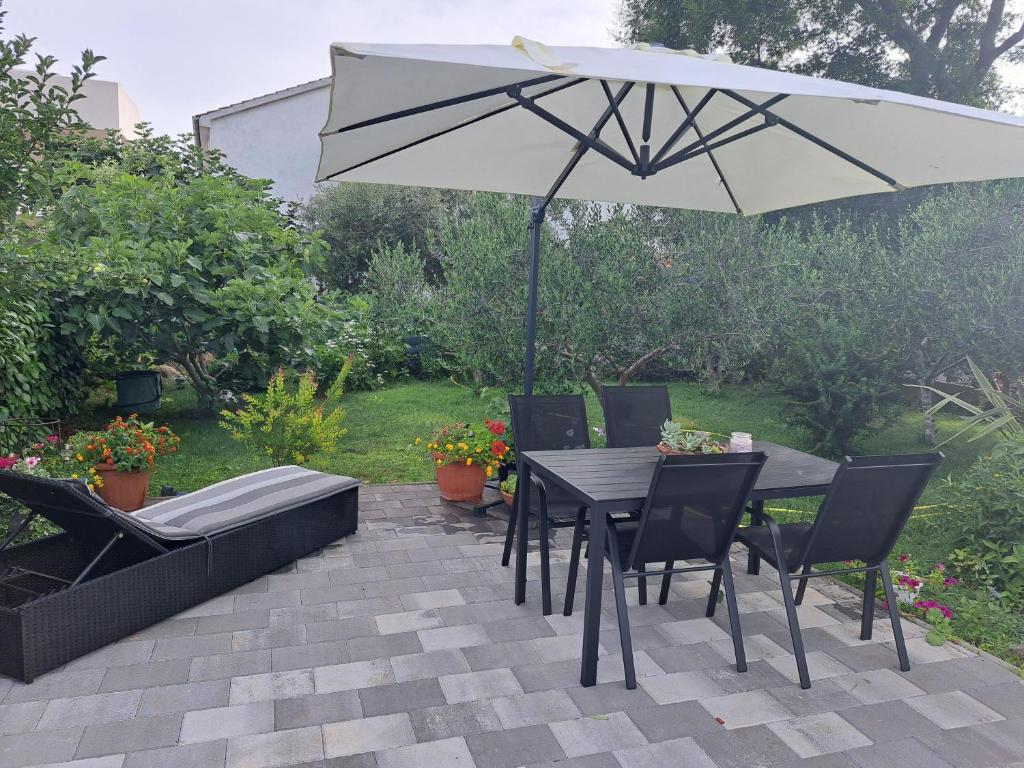um pátio com um guarda-sol, uma mesa e cadeiras em Apartment Noa's Garden em Bibinje