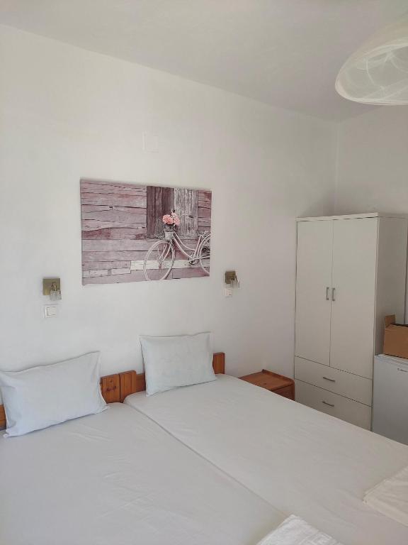 a bedroom with a white bed with a bike on the wall at Ios Penelope in Ios Chora