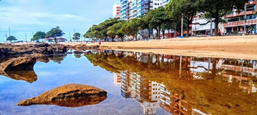 un reflet d'une plage et de bâtiments dans l'eau dans l'établissement Vem pra cá! Localização Privilegiada!, à Guarapari