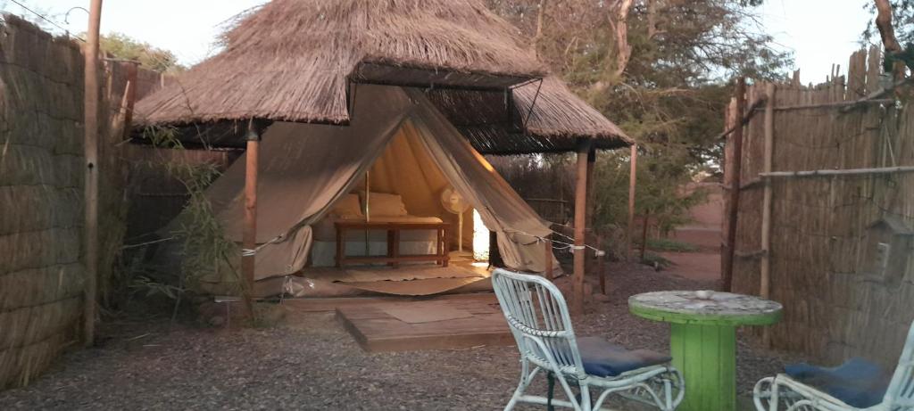 uma pequena cabana com uma mesa e uma cadeira em frente em Aji Verde Hostel San Pedro em San Pedro de Atacama