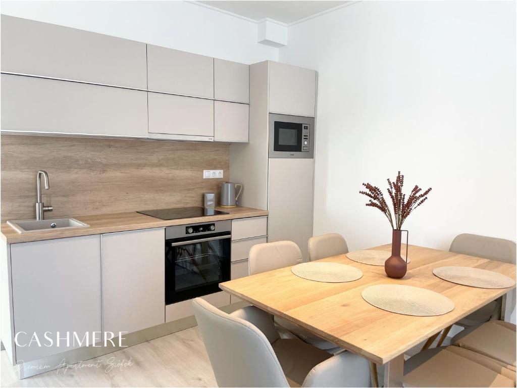 a kitchen with a wooden table and white cabinets at CASHMERE Premium Apartment in Siófok