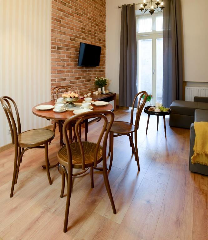Open living-dining space with wooden dining set, brick-accent wall TV, gray curtains, and cozy ambiance