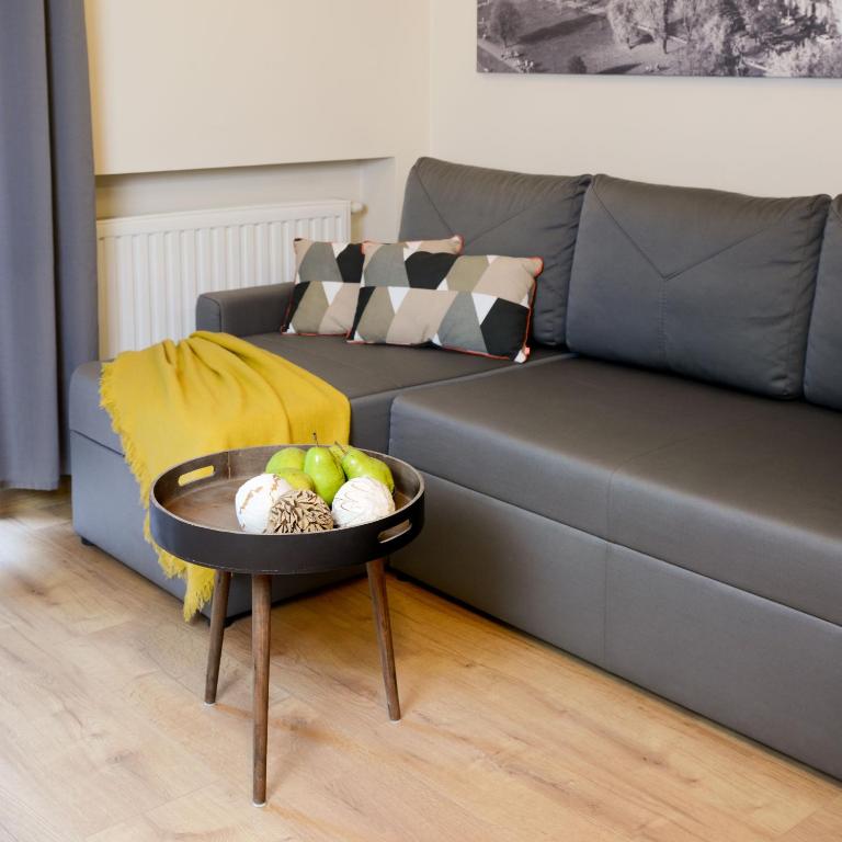 Gray sofa with patterned pillows and yellow throw, small round tray table holding pears and decorative balls