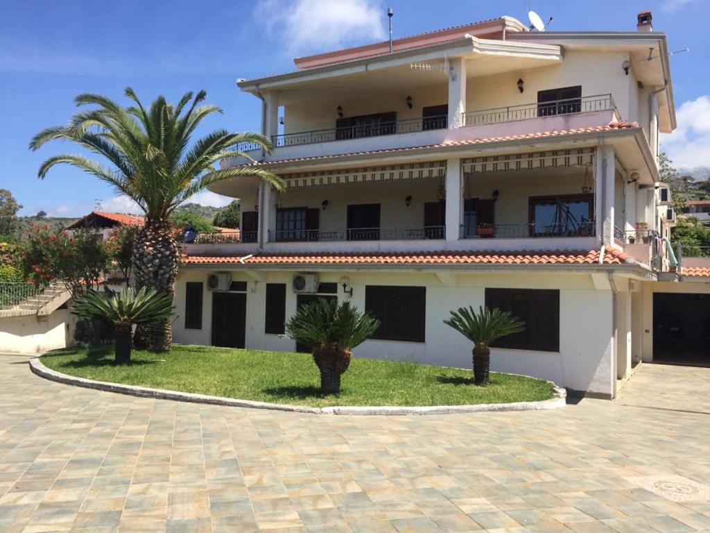 uma grande casa branca com palmeiras em frente em Villa Greco em Cirella