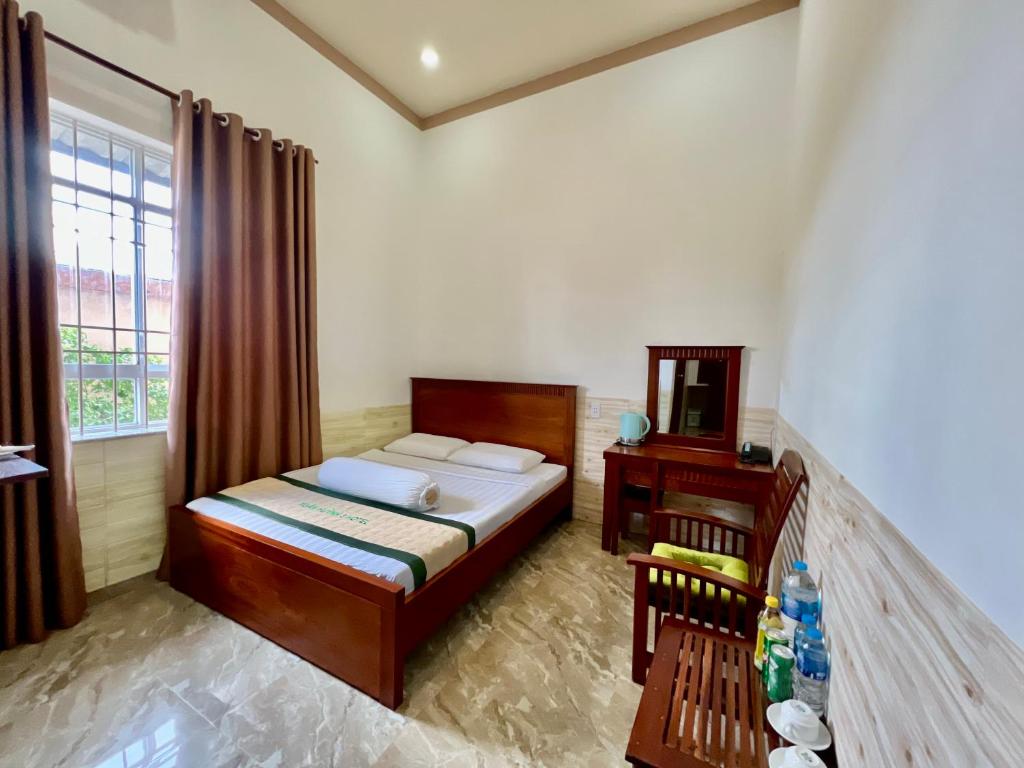 um quarto com uma cama, uma mesa e uma janela em XUÂN HUỲNH 3 Hotel em Soc Trang