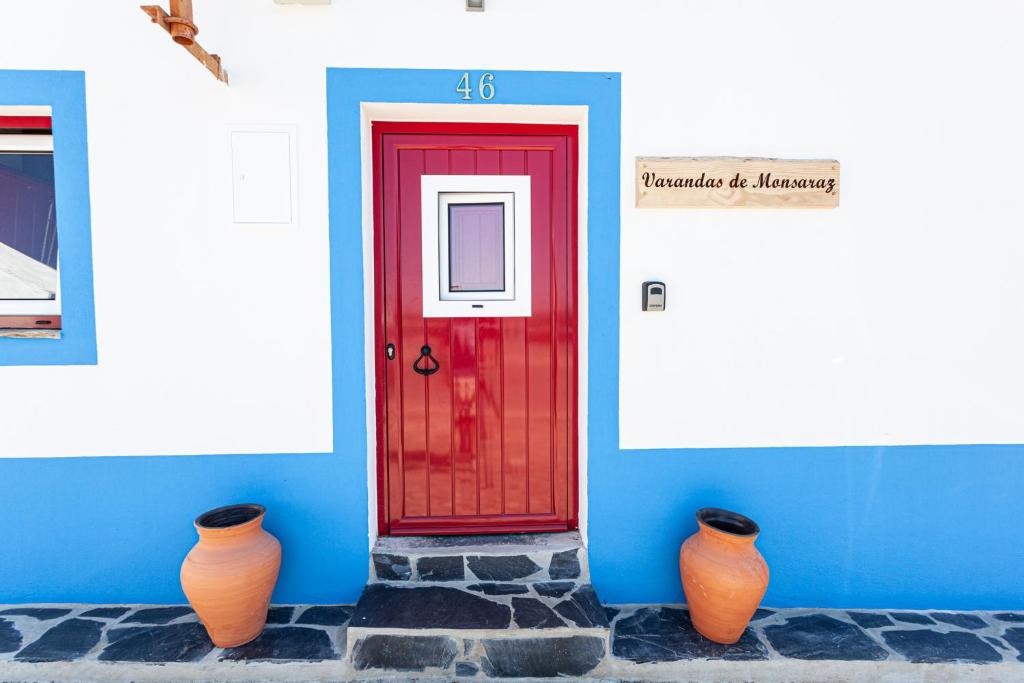 due vasi arancioni seduti di fronte a una porta rossa di Varandas de Monsaraz a Monsaraz