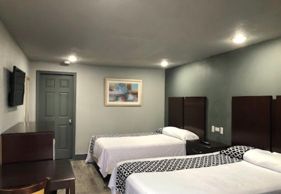 a hotel room with two beds and a table and a room at Budget Inn Valparaiso/Niceville @ Eglin AFB & Destin-FWB Airport in Niceville