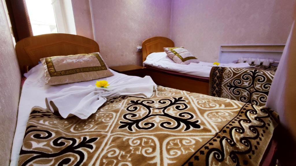 twee bedden in een kleine kamer met rokken bij Zheenkan2 in Naryn