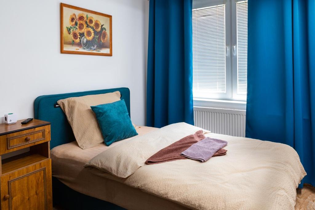 a small bedroom with blue curtains and a bed at Penzión Rozália in Košice