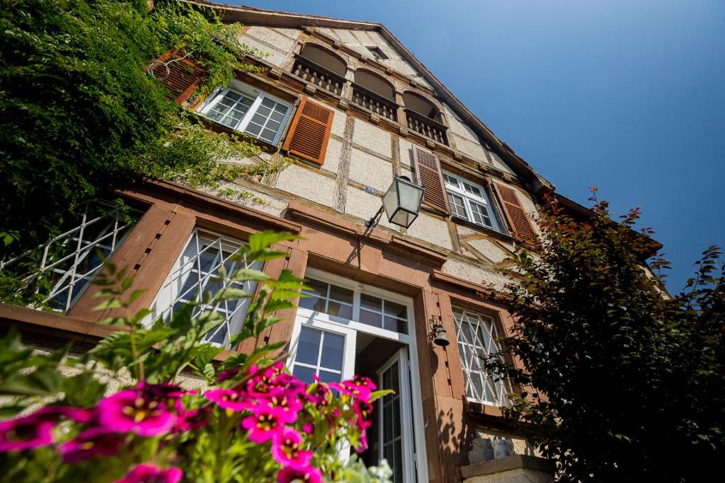 a building with pink flowers in front of it at Le Clos d'Azel MAISON D'HOTES in Flexbourg