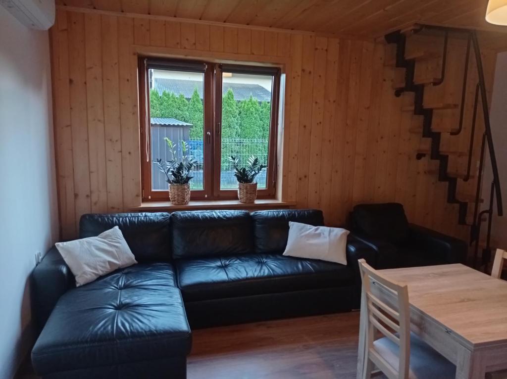 ein Wohnzimmer mit einem schwarzen Ledersofa und einem Tisch in der Unterkunft apartamentyDvorskie in Nowy Sącz