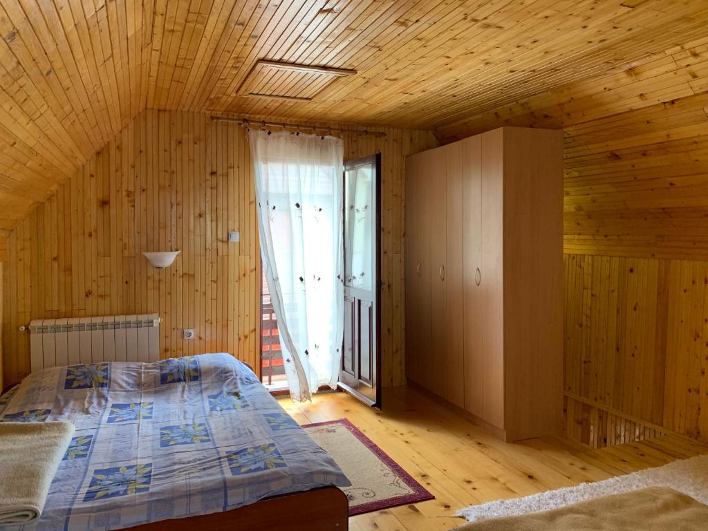 een slaapkamer met een bed en een houten plafond bij Vikendica Klara in Žabljak
