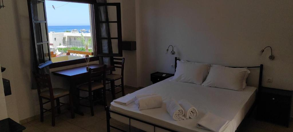 1 dormitorio con cama, escritorio y ventana en Dedalos n3 Sea View apartment-30 metres from the beach, en Stalida