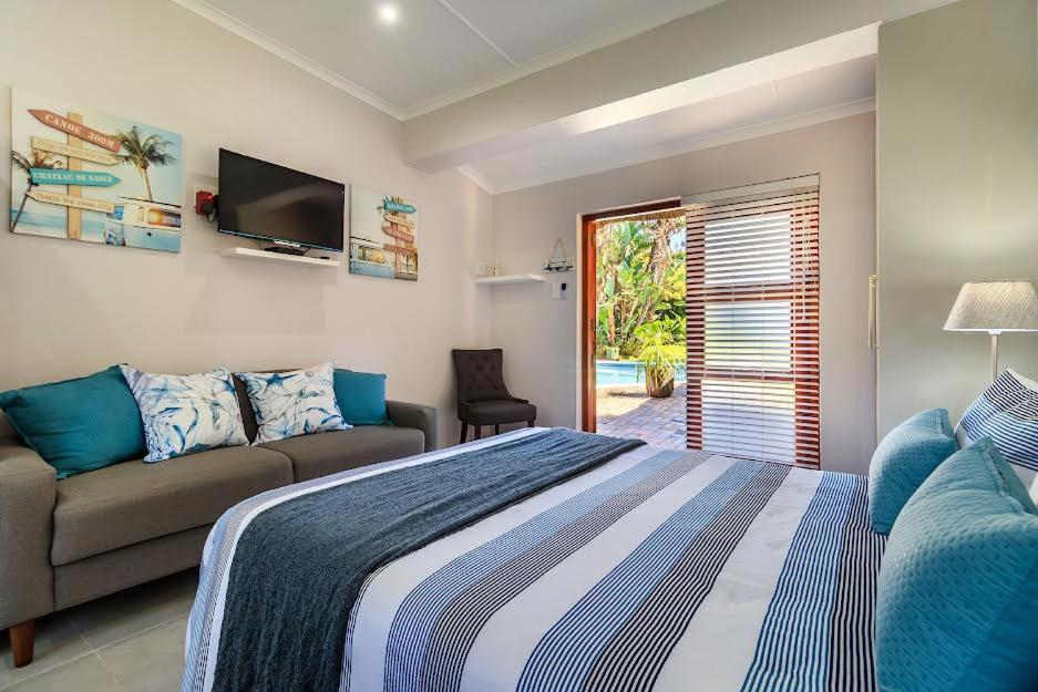 a bedroom with a bed and a couch at Unit 2a @ The Thatches in Kei-mouth Village