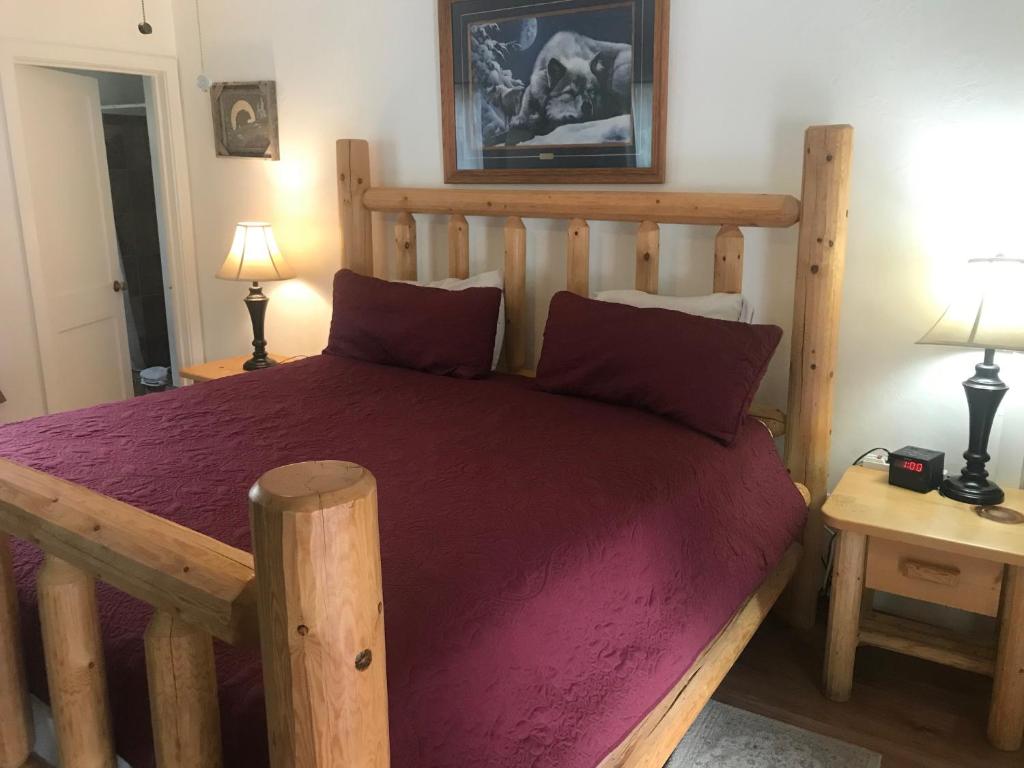 a bedroom with a wooden bed with purple sheets at Dunsmuir Lodge in Dunsmuir