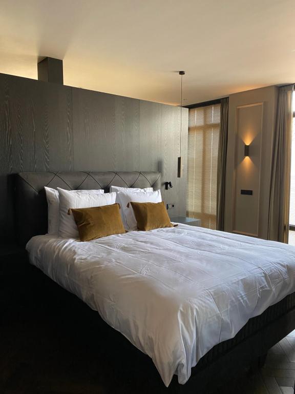 a bedroom with a large white bed with yellow pillows at Brabant Suites in Nistelrode