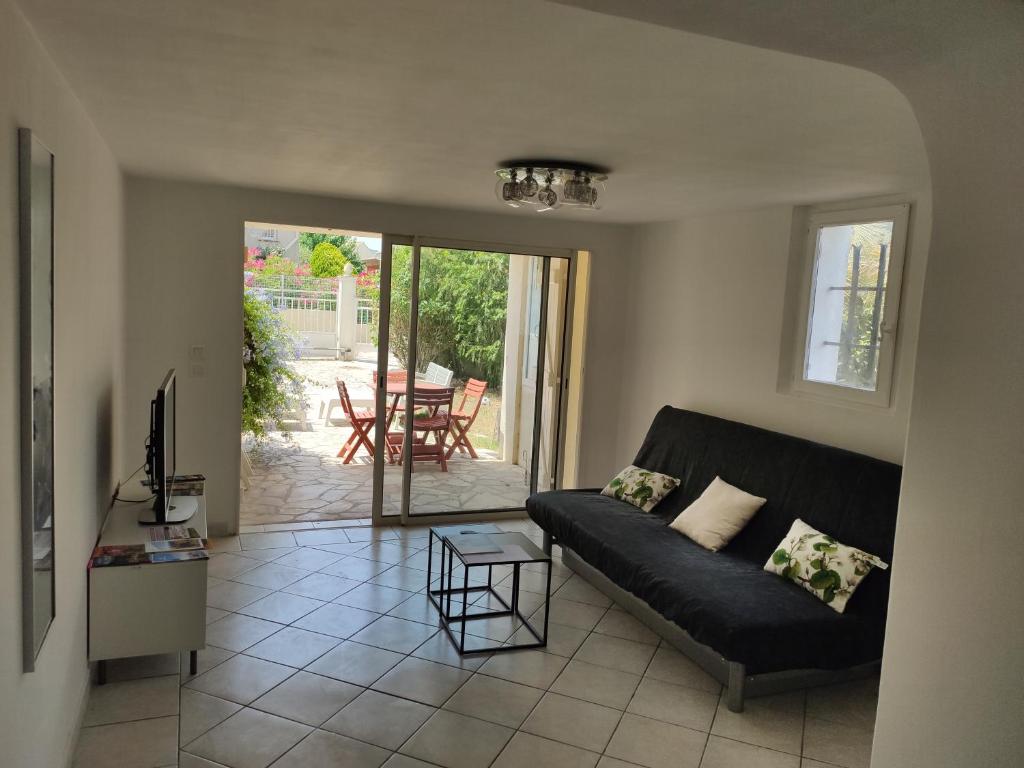 uma sala de estar com um sofá preto e uma mesa em Appartement T2 Roquebrune sur Argens em Roquebrune-sur-Argens