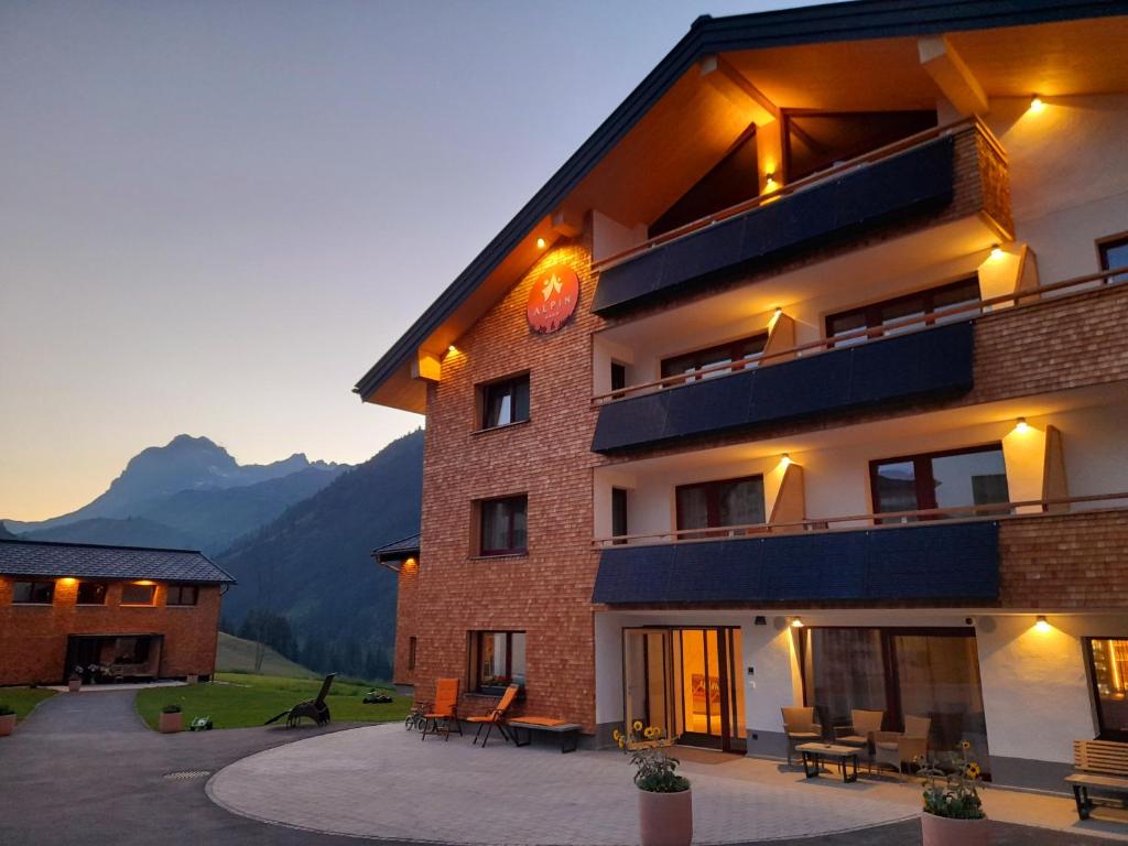 un gran edificio con mesas y sillas delante de él en Alpin - Studios & Suites, en Warth am Arlberg