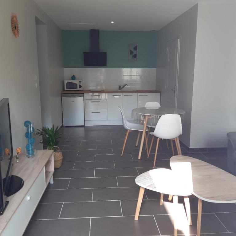 eine Küche mit 2 Tischen und weißen Stühlen in einem Zimmer in der Unterkunft le studio de Bruno in Alençon