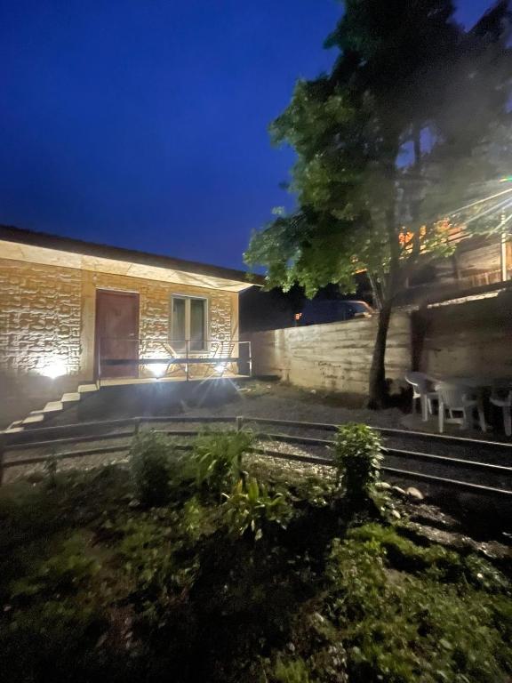una casa con un árbol y un edificio por la noche en Cottage - Location Lanchvali, en Mestia
