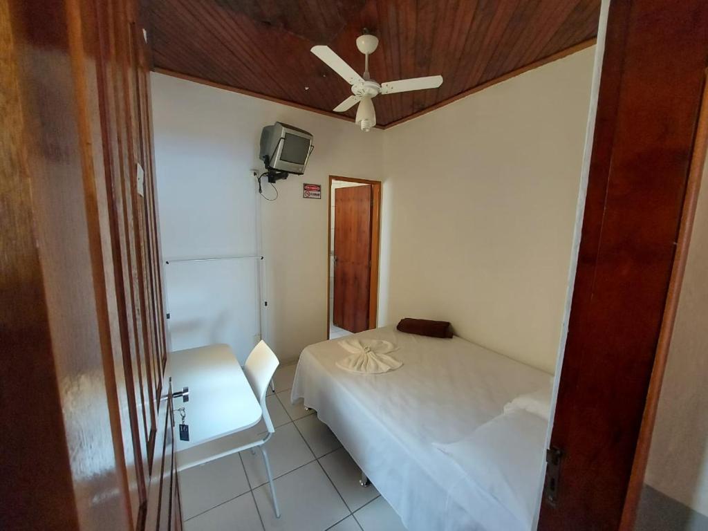 a bedroom with a bed and a ceiling fan at Novo Hotel in Itajubá