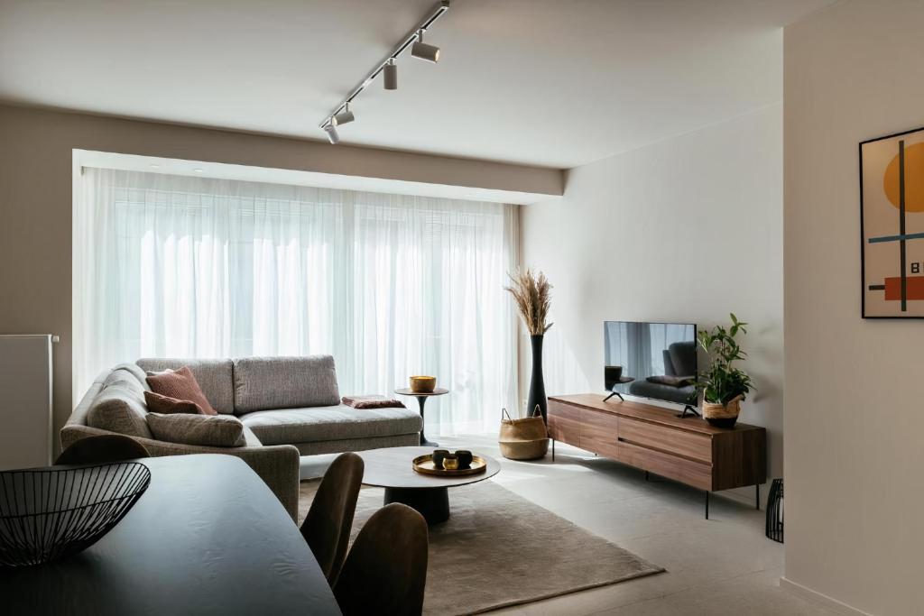 a living room with a couch and a tv at - Carijoca - Gemoderniseerd, lichtrijk & zijdelings zeezicht app in Koksijde