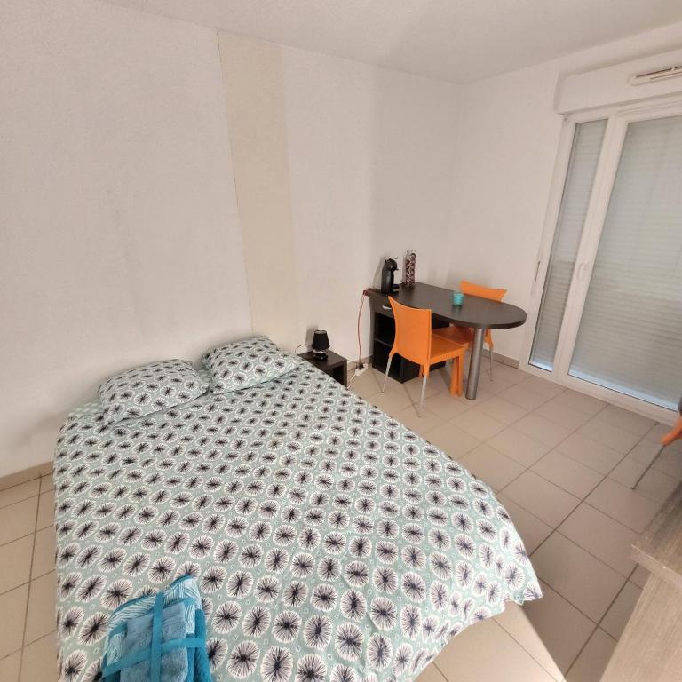 une chambre avec un lit et une table dedans dans l'établissement Studio équipé face CHU, à Saint-Priest-en-Jarez