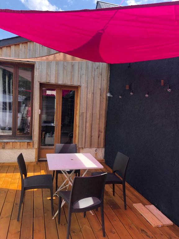 un patio con mesa y sillas bajo una sombrilla roja en Adorable petite maison sur Loire à vélo en Villandry