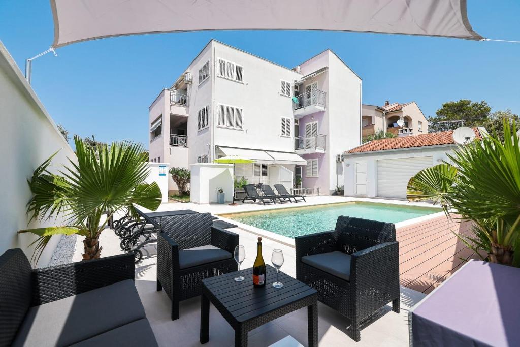 a patio with a table and chairs and a swimming pool at Apartmani Leona in Bibinje