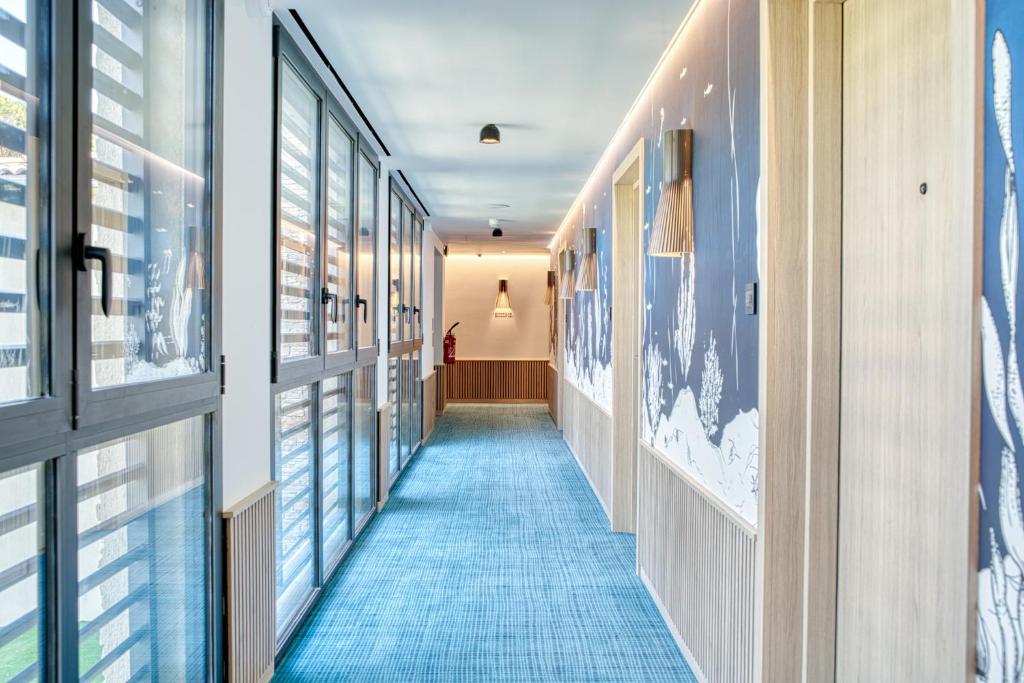 a hallway with a blue carpet and windows at EDEN HÔTEL in Sainte-Maxime