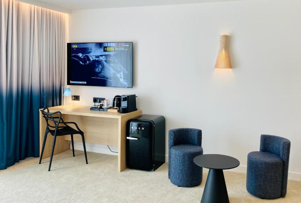 a room with a desk with a tv and two chairs at EDEN HÔTEL in Sainte-Maxime