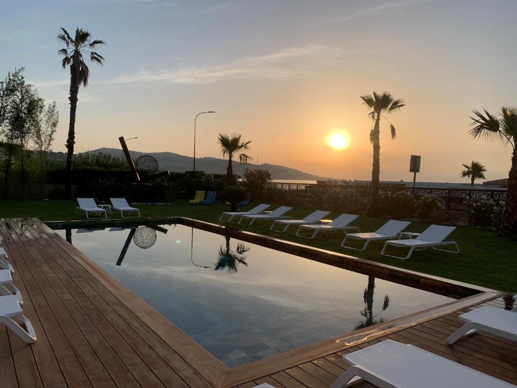 a pool with chairs and the sunset in the background at EDEN HÔTEL in Sainte-Maxime