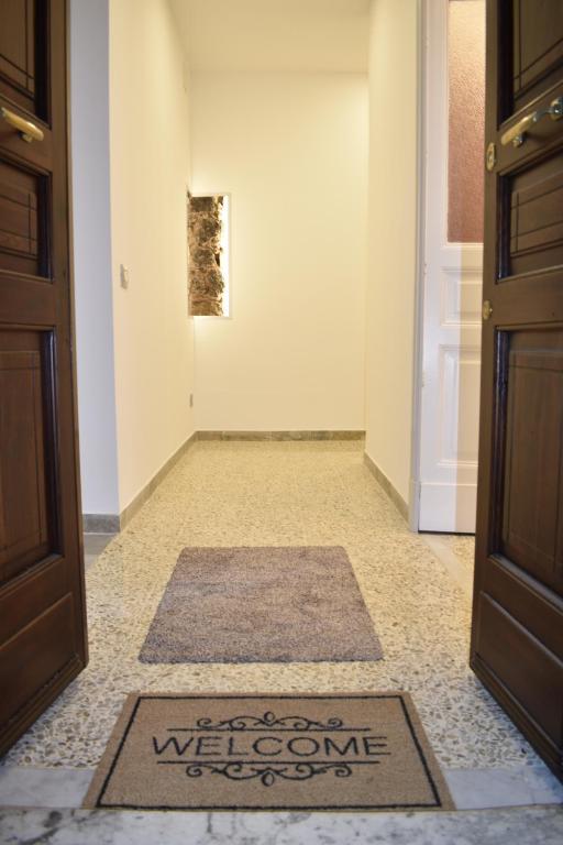 um corredor com um tapete de boas-vindas no chão ao lado de uma porta em La Dagala em Catânia