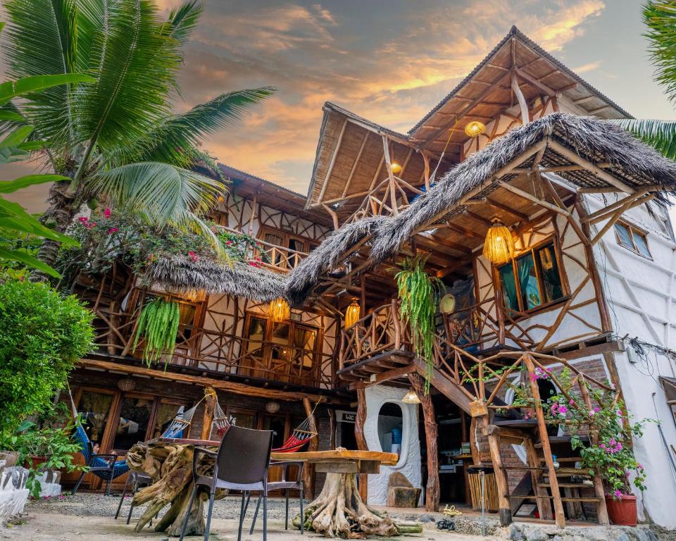 a wooden house with a table and chairs in front of it at Hostal Rutamar in Canoa
