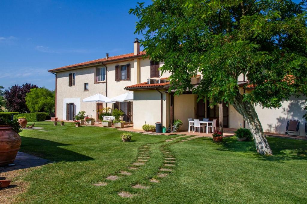 a house with a green yard with a tree at Agriturismo Il Poggiolo in Grosseto