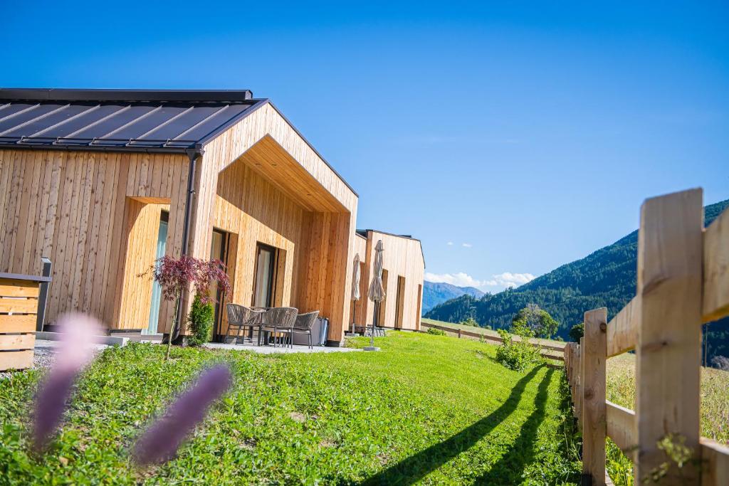 a wooden house on a hill with a fence at Ganovhof - Deluxe Chalet in San Valentino alla Muta