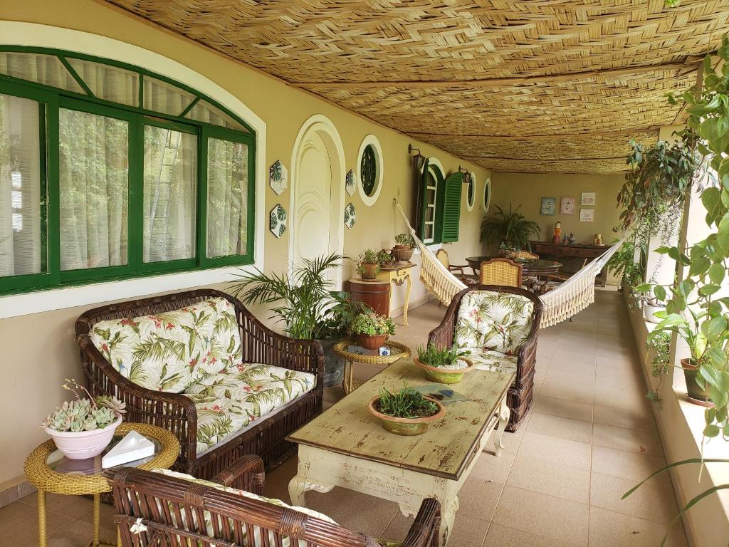 un porche con sofás, una mesa y algunas plantas en Sitio Natividade en Delfim Moreira