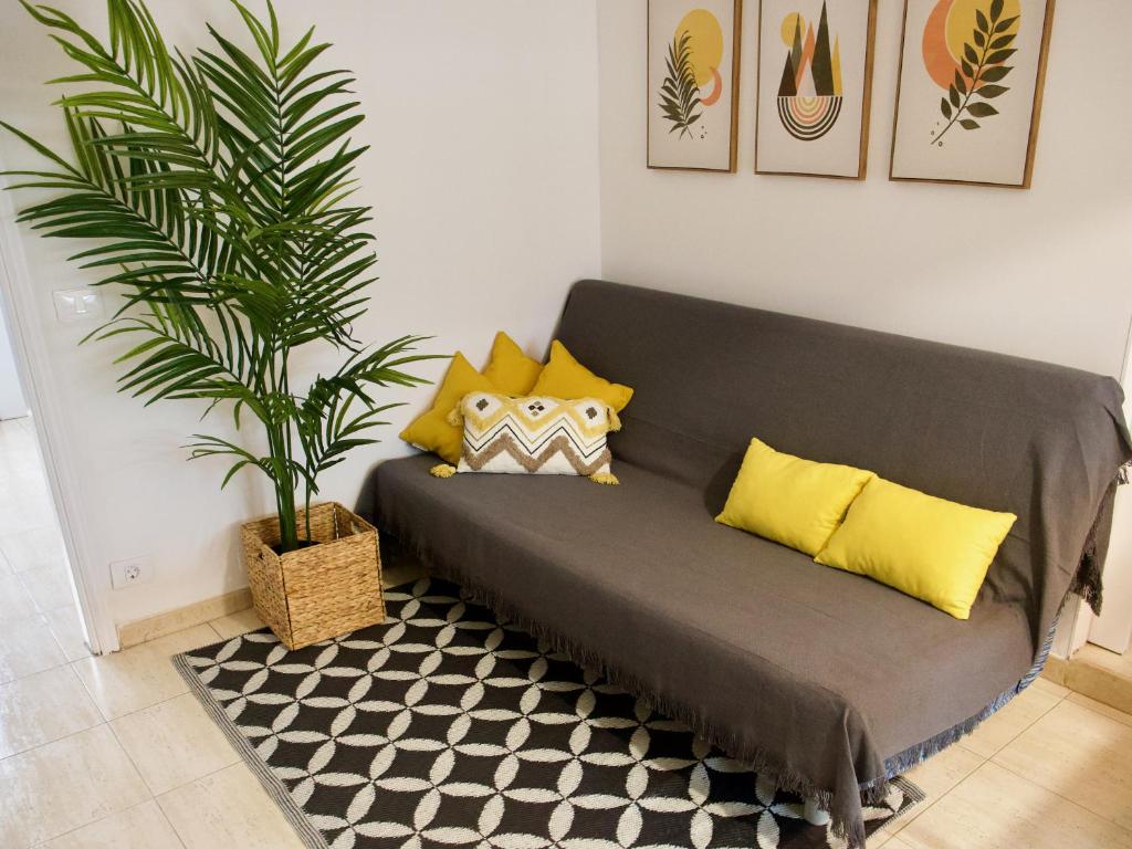 a couch with yellow pillows and a plant in a room at APARTAMENTO PLAYA ALCARAVANERAS in Las Palmas de Gran Canaria