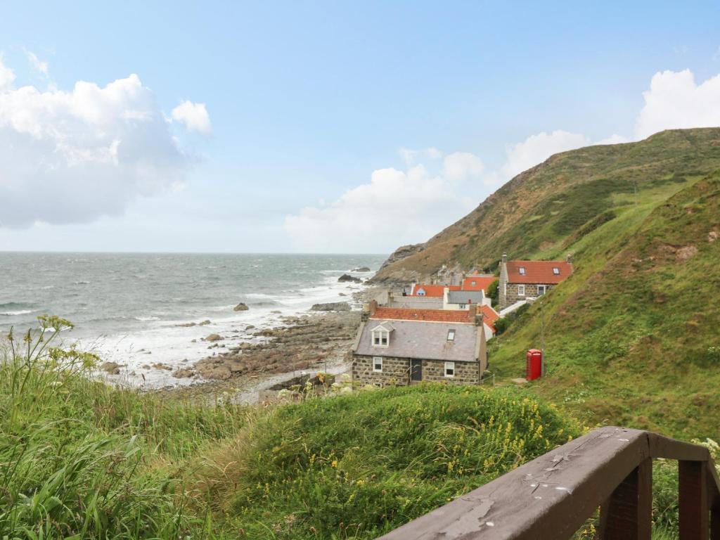a group of houses on a hill next to the ocean at 49 Crovie Village in Gardenstown