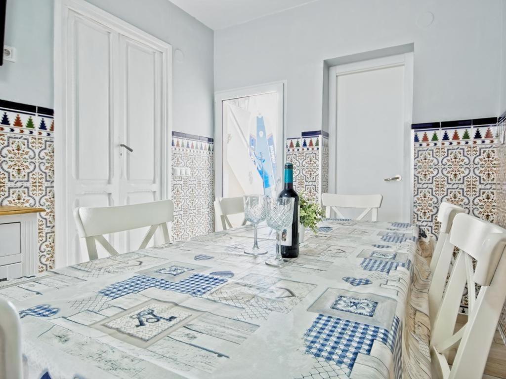 a white dining room with a table with a bottle of wine at CASA EN LA PLAYA VALENCIA EL PERELLO in Mareny Barraquetas