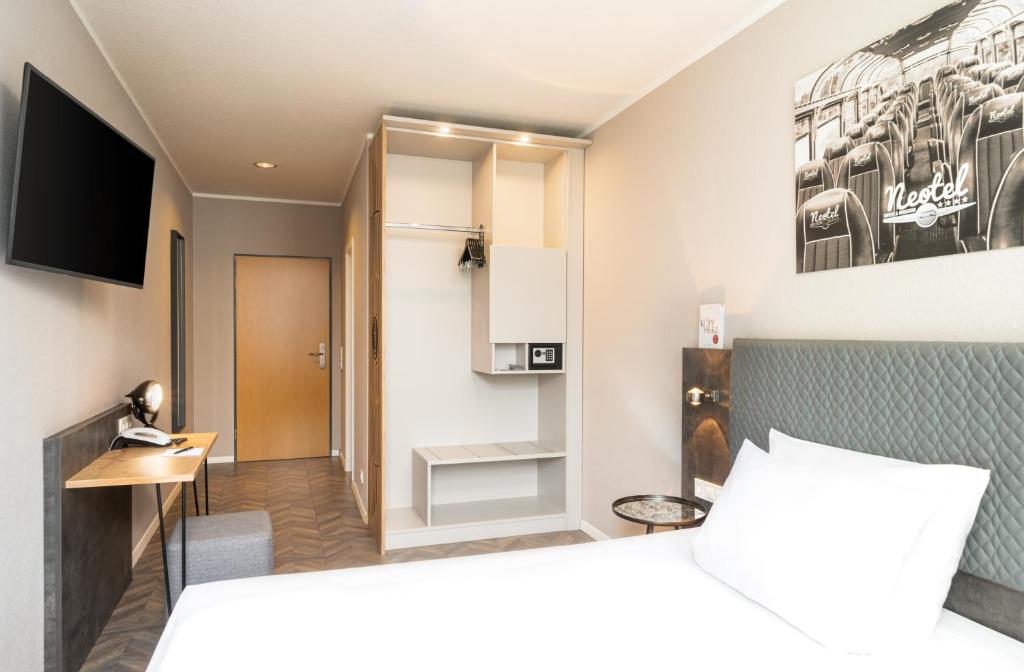 a hotel room with a bed and a tv at Arthotel ANA Neotel in Stuttgart