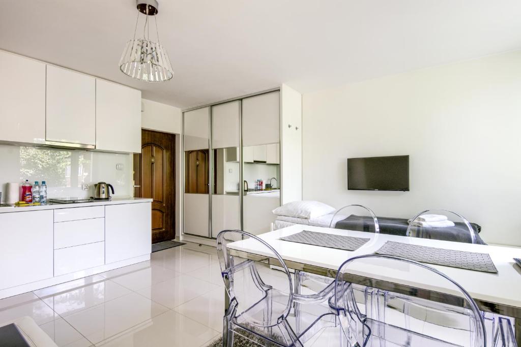 uma cozinha com armários brancos e uma mesa e cadeiras em Sea You Apartments - Chrobrego em Sopot