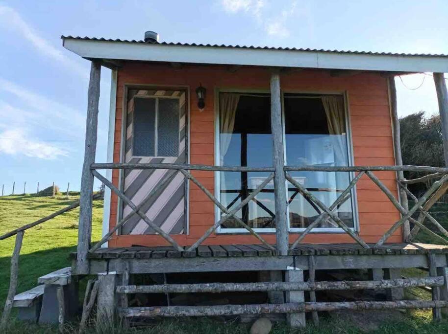 une petite maison sur une colline avec une terrasse couverte dans l'établissement Cabaña pumillahue rural, à Ancud