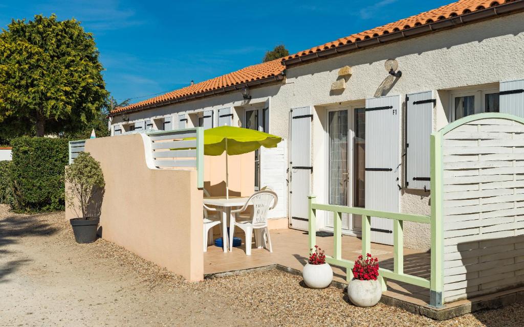 une petite terrasse avec une table et un parasol dans l'établissement Lagrange Vacances Les Maisons de Saint Georges, à Saint-Georges-de-Didonne